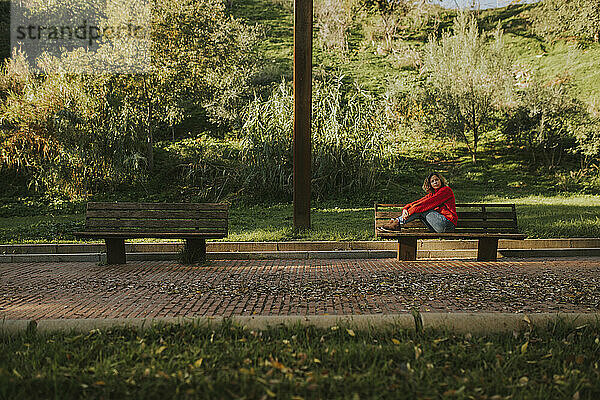 Woman sitting on bench near trees in autumn park