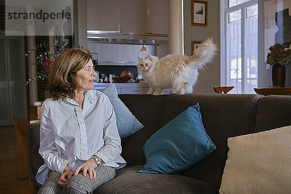 Mature woman with Persian cat on sofa at home
