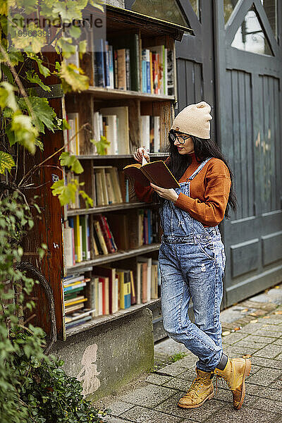 Frau mit beigem Strickhut liest Buch in Buchhandlung