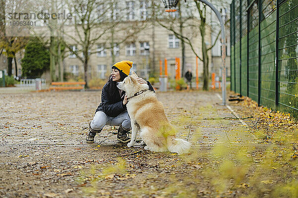 Glückliche Frau streichelt Akita-Hund im Herbstpark
