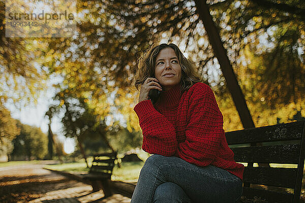 Nachdenkliche Frau sitzt auf einer Bank im Herbstpark