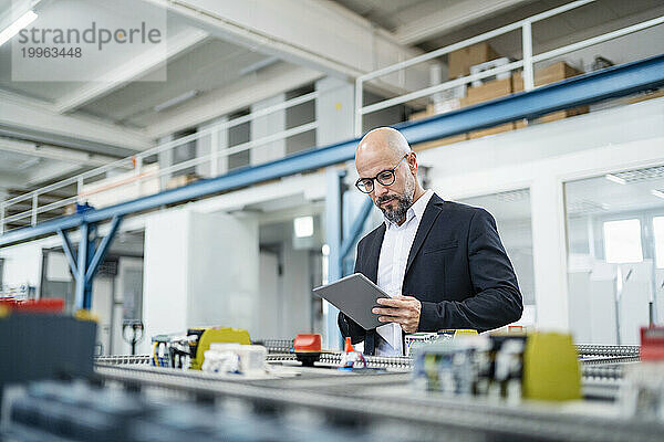 Ingenieur nutzt Tablet-PC in der Nähe von Maschinen in der Fabrik