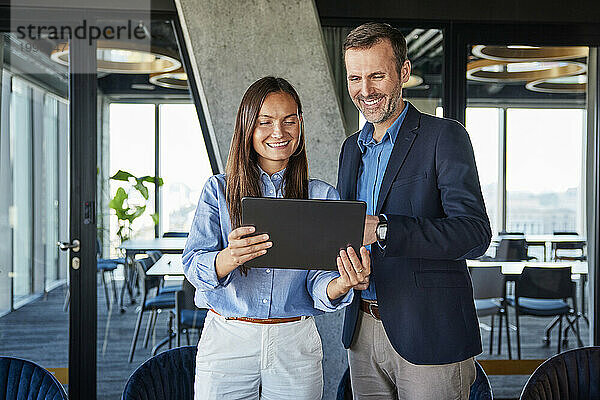 Glückliche Geschäftsfrau und Geschäftsmann diskutieren über Tablet-PC