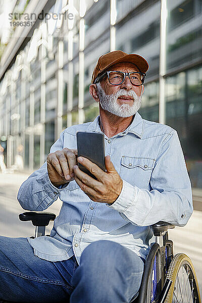 Rentner älterer Mann sitzt im Rollstuhl und benutzt Smartphone