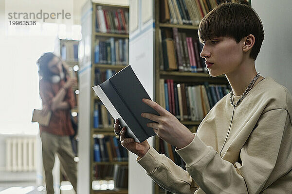 Junger Student liest Buch in der Bibliothek