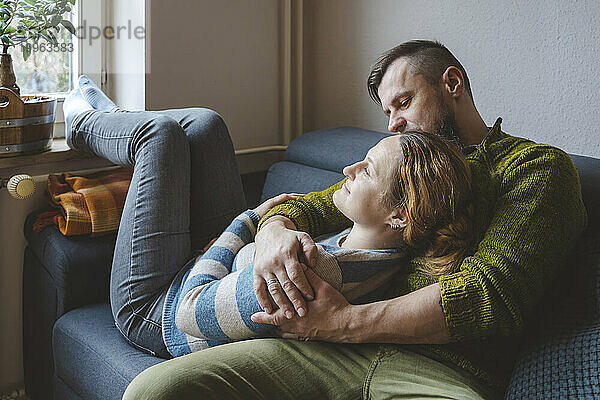 Mann umarmt Frau auf Sofa zu Hause