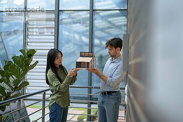 Multiracial architects examining model house standing in corridor