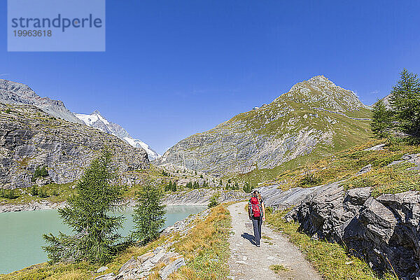 Reife Frau spaziert in der Nähe des Margaritze-Stausees unter blauem Himmel im Nationalpark Hohe Tauern  Salzburg  Österreich