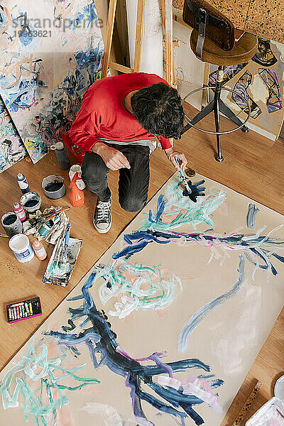 Reifer Künstler malt im Kunstatelier mit Pinsel auf Leinwand