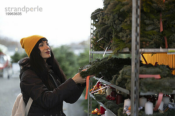 Schöne Frau kauft Kranz auf dem Weihnachtsmarkt