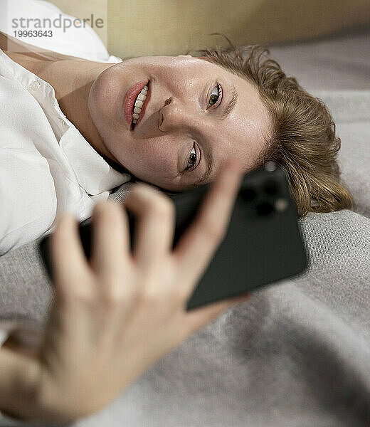 Lächelnde Frau  die zu Hause ihr Smartphone benutzt