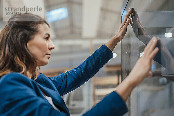 Geschäftsfrau berührt den Bildschirm eines Computers in der Industrie