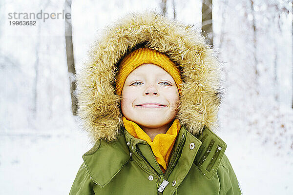 Lächelnder Junge im Parka-Mantel im Winter