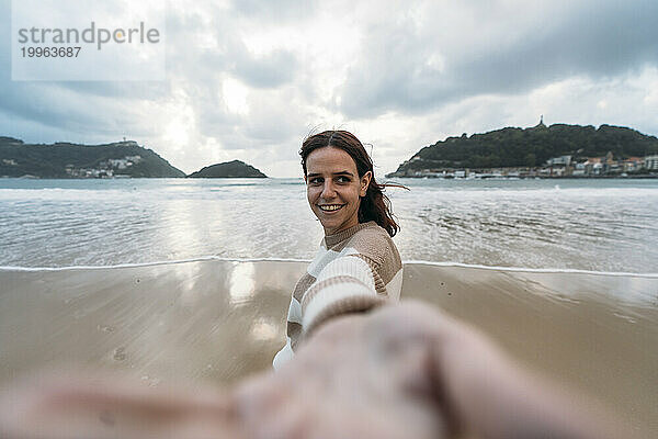 Junge Frau am Ufer der Playa de la Concha unter bewölktem Himmel