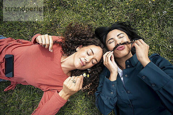 Gemischtrassige Frauen liegen mit geschlossenen Augen auf Gras im Park