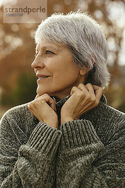 Lächelnde reife Frau mit grauem Haar und Pullover