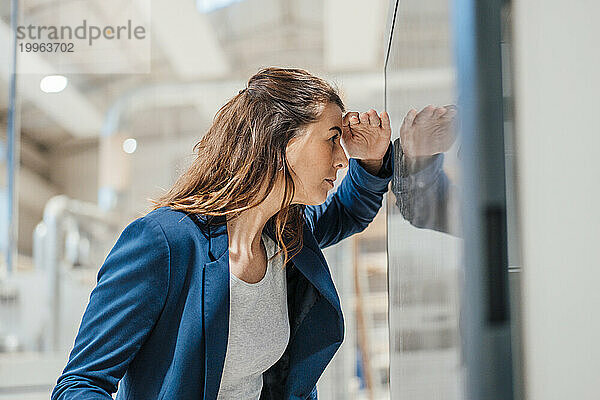 Geschäftsfrau blickt in Werkstatt auf Computerbildschirm