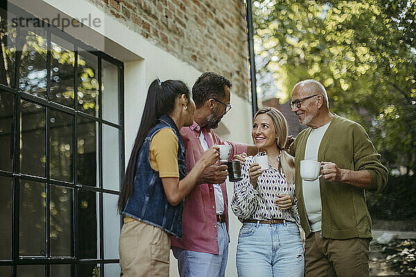 Menschen bei einem Gemeindetreffen stehen draußen und reden und trinken Kaffee