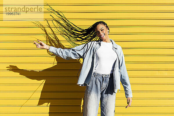 Happy young woman tossing hair in front of corrugated shutter