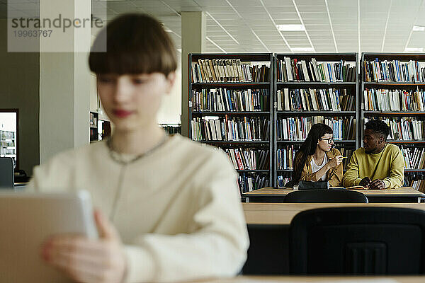 Junge Studenten diskutieren in der Bibliothek