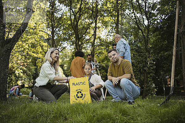 Sozial integrative Gruppe von Freiwilligen  die Plastikmüll in Recyclingtüten werfen