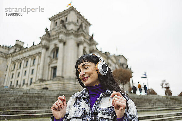 Eine lächelnde Frau hört gerne Musik über kabellose Kopfhörer
