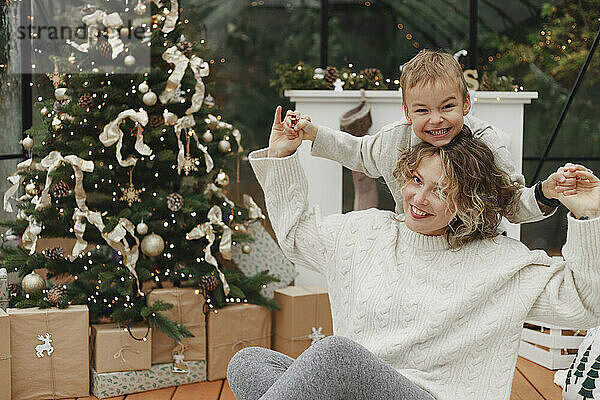 Glückliche Mutter und Sohn  die zu Hause Spaß am Weihnachtsbaum haben