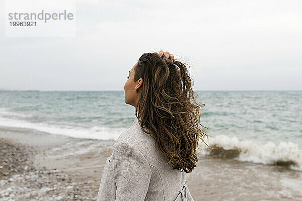 Frau mit der Hand im Haar am Strand