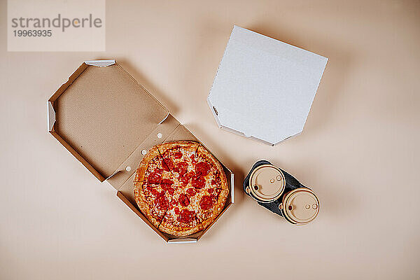 Pepperoni pizza near coffee cups against beige background