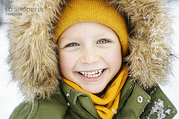 Fröhlicher Junge im Parka-Mantel im Schnee