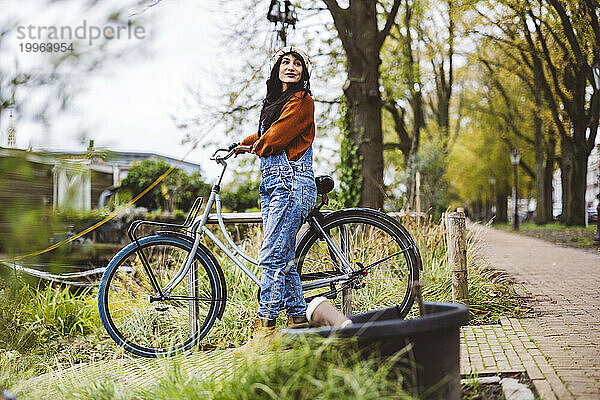 Lächelnde Frau  die mit dem Fahrrad auf dem Fußweg läuft