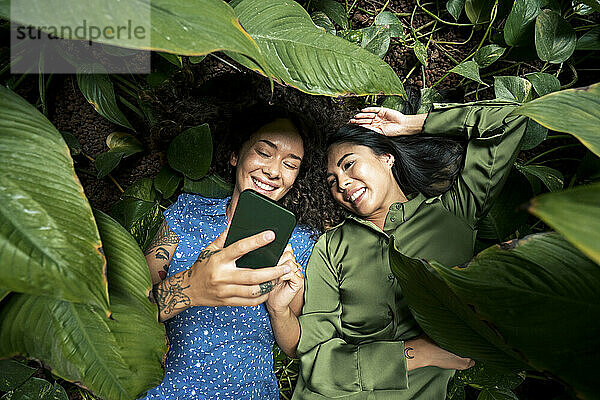 Lächelnde Frau macht Selfie mit Smartphone mit Freund im Park
