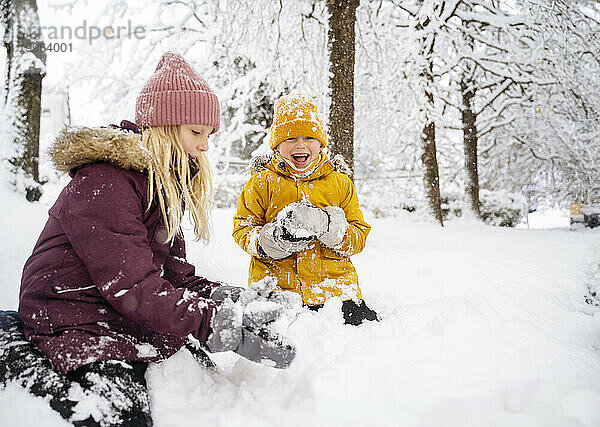 Glücklicher Bruder und Schwester  die im Schnee spielen