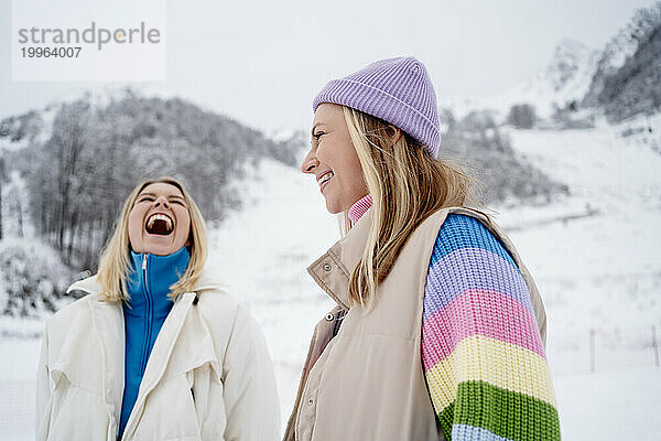 Blonde Freunde lachen auf schneebedecktem Berg