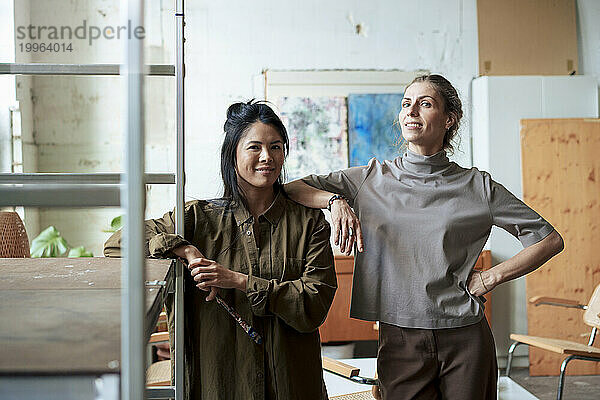 Women standing by rack in art studio