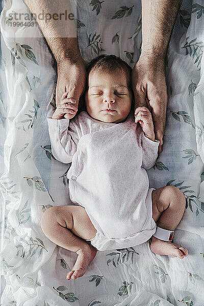 Hands of father holding sleeping baby girl