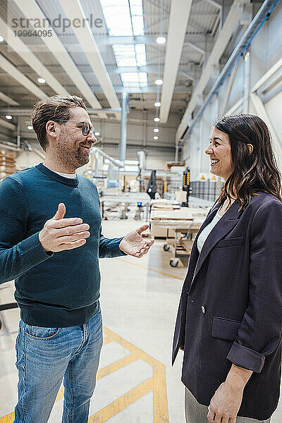 Fröhliche Geschäftskollegen diskutieren  während sie in der Werkstatt stehen