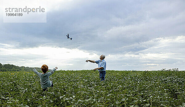 Großvater und Enkel fliegen Spielzeugflugzeug im Feld