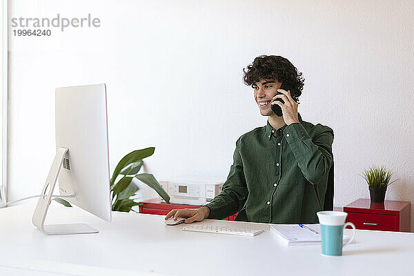 Lächelnder Geschäftsmann beim Multitasking im Heimbüro