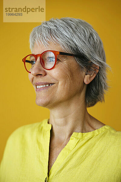 Lächelnde Frau mit Brille vor gelbem Hintergrund