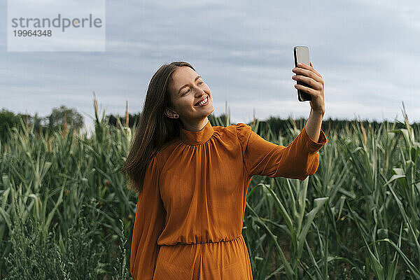 Glückliche Frau  die ein Selfie vor Maispflanzen auf dem Feld macht