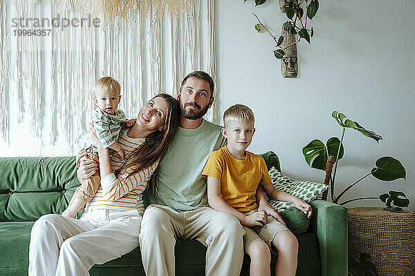 Porträt einer Familie mit zwei Söhnen  die auf der Couch im Wohnzimmer sitzen