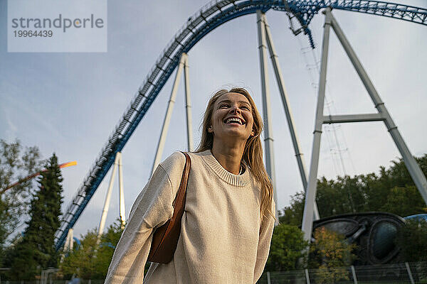 Happy woman laughing and standing in front of rollercoaster