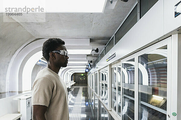 Man wearing futuristic glasses standing at metro station