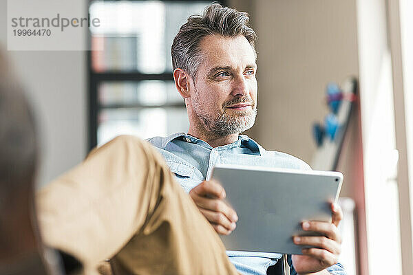 Geschäftsmann sitzt mit Tablet-PC in der Hand