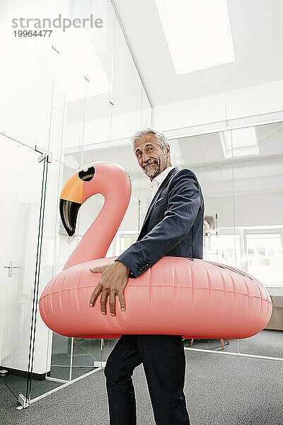 Geschäftsmann im Büro mit aufblasbarem Flamingo