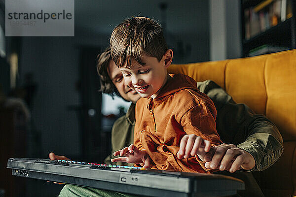 Lächelnder Vater bringt seinem Sohn zu Hause das E-Piano-Spielen bei