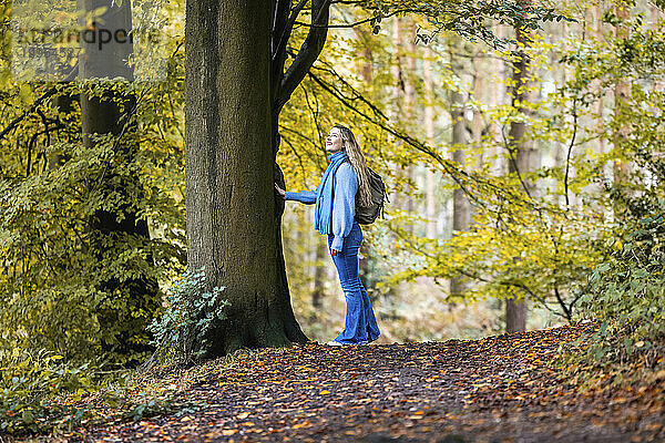 Lächelnde Frau steht neben einem Baum im Cannock Chase Forest