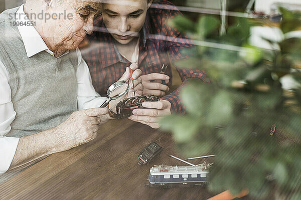Großvater repariert Miniatureisenbahn mit Enkel zu Hause
