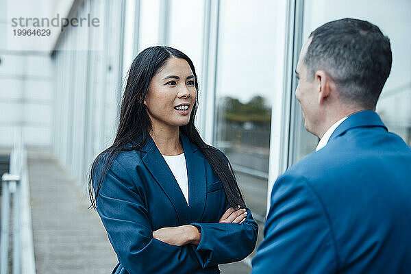 Lächelnde Geschäftsfrau und Geschäftsmann diskutieren in der Nähe von Gebäude